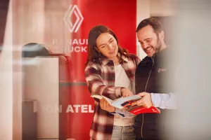 Un vendedor Renault Trucks y una clienta conversando alrededor de un folleto.