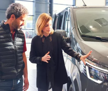 Trafic E-TECH in a dealers store with two people next to it